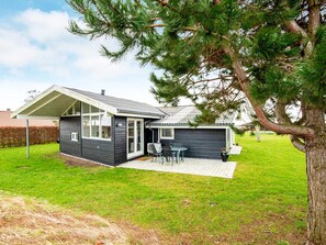A modern two-story house with a patio area, a covered outdoor seating space, and a large tree in the foreground. - 8 Person Holiday Home in Ebeltoft-by Traum (Ebeltoft)