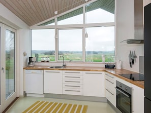 A modern kitchen with a large window, wooden ceiling, and stainless steel appliances.