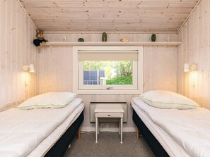 A room with two beds, a window, a desk, and a shelf with decorative items. - 4 Star Holiday Home in Otterup (Otterup)