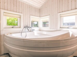 A modern bathroom with a freestanding bathtub, wooden walls, and windows with views of greenery. - 4 Star Holiday Home in Otterup (Otterup)