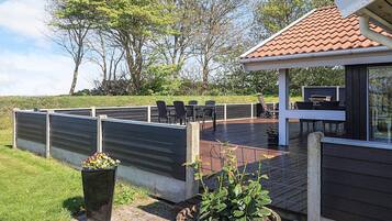 A deck with outdoor furniture, a barbecue grill, and a garden area with potted plants.