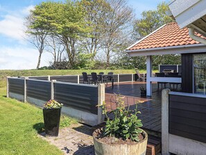 A deck with outdoor furniture, a barbecue grill, and a garden area with potted plants. - 4 Star Holiday Home in Otterup (Otterup)