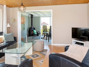 A modern living room with a glass coffee table, leather sofas, a flat-screen TV, and a fireplace.
