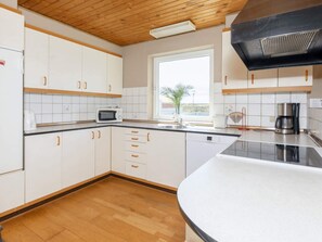 A modern kitchen with white cabinets, a microwave, a Bosch dishwasher, and a coffee maker.