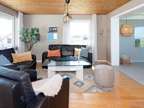 A modern living room with leather sofas, a glass coffee table, and a large window with curtains.