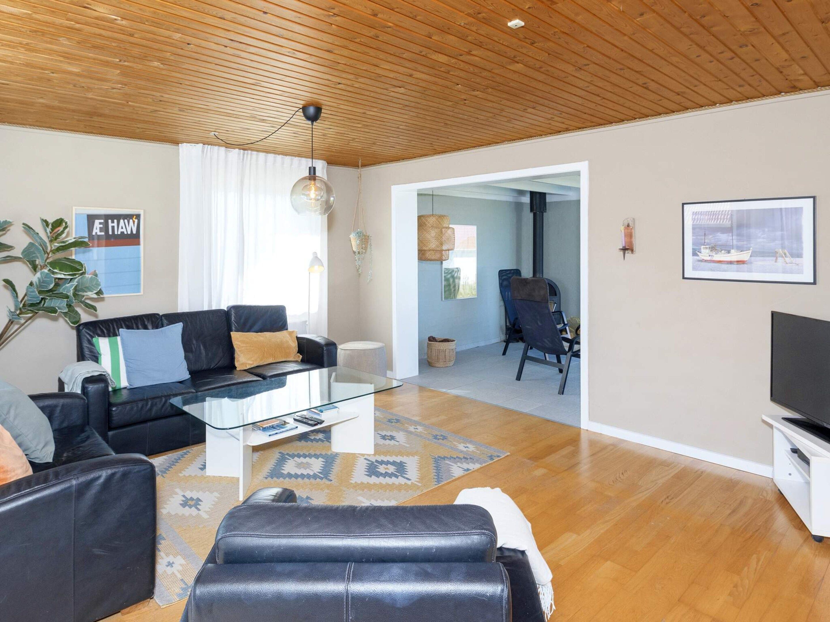 En moderne stue med en lædersofa, et glasbord og et fjernsyn.