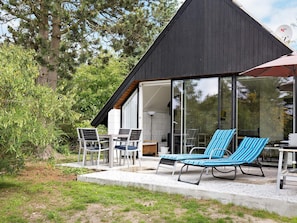 A modern outdoor seating area with a glass enclosure, a table, and chairs. - Quaint Holiday Home in Sjaellands Odde near Sea (Sjællands Odde)