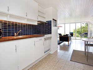 A modern kitchen with white cabinets, a wooden countertop, and a blue-tiled backsplash. - Quaint Holiday Home in Sjaellands Odde near Sea (Sjællands Odde)