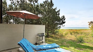 A patio with two lounge chairs, a table, and an umbrella.