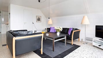 Moderni olohuone, jossa on sohva, sohvapöytä ja kaksi lamppua.