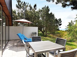 An outdoor patio with a table and chairs, a grill, and a large umbrella. - Quaint Holiday Home in Sjaellands Odde near Sea (Sjællands Odde)