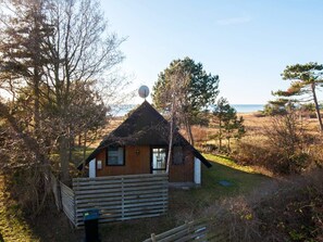 A small wooden cabin with a thatched roof, surrounded by trees and a grassy field. - Quaint Holiday Home in Sjaellands Odde near Sea (Sjællands Odde)