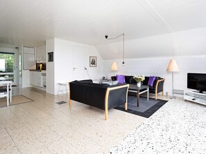 Un interior modern amb zona de menjador, sofà, televisió i cuina.