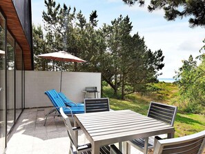 A patio with a table and chairs, a grill, and an umbrella. - Quaint Holiday Home in Sjaellands Odde near Sea (Sjællands Odde)