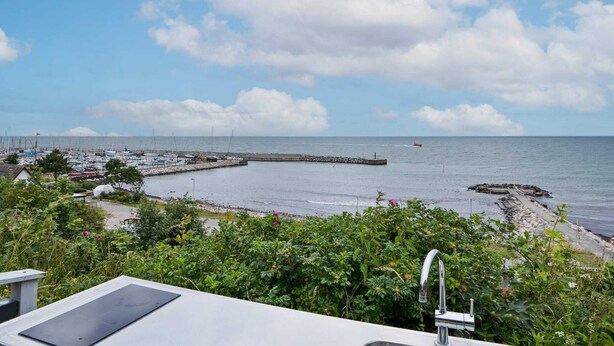 A coastal view with a marina, rocky breakwater, and lush greenery. - 12 Person Holiday Home in Sjaellands Odde-by Traum (Sjællands Odde)