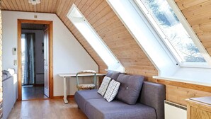 A cozy attic bedroom with a sloped ceiling, a grey sofa, a small table, and a window. - 12 Person Holiday Home in Sjaellands Odde-by Traum (Sjællands Odde)