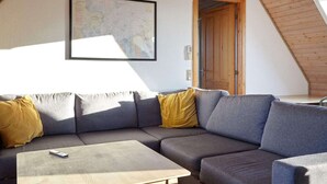 A modern living room with a sectional sofa, a coffee table, and a map on the wall. - 12 Person Holiday Home in Sjaellands Odde-by Traum (Sjællands Odde)