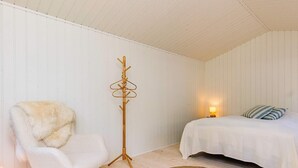 A room with a bed, a chair, a floor lamp, and a woven rug. - 6 Person Holiday Home in Gilleleje-by Traum (Gilleleje)