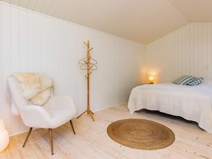 A room with a bed, a chair, a floor lamp, and a woven rug. - 6 Person Holiday Home in Gilleleje-by Traum (Gilleleje)