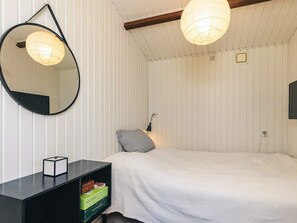 A bedroom with a bed, a round mirror, a bedside lamp, and a small black nightstand with a box. - 6 Person Holiday Home in Gilleleje-by Traum (Gilleleje)