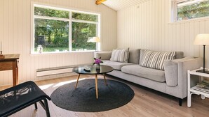 A living room with a sofa, a coffee table, a lamp, and a window with a view of greenery. - 6 Person Holiday Home in Gilleleje-by Traum (Gilleleje)
