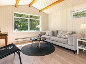 A living room with a sofa, a coffee table, a lamp, and a window with a view of greenery. - 6 Person Holiday Home in Gilleleje-by Traum (Gilleleje)