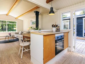 A modern kitchen with a central island, wooden beams, a black pendant light, and a view of the outdoors. - 6 Person Holiday Home in Gilleleje-by Traum (Gilleleje)