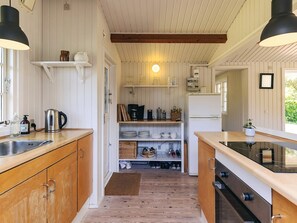 Une cuisine de taille réduite, dotée de meubles en bois, d’un four encastré et d’un réfrigérateur.