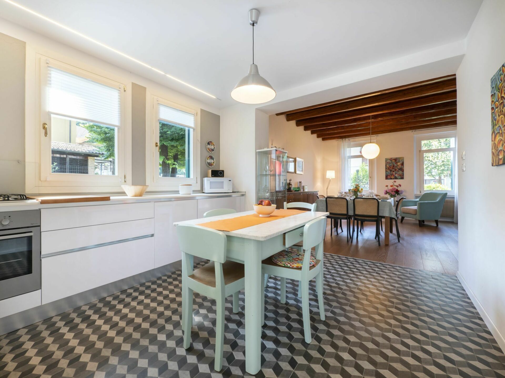 Une cuisine moderne avec un coin repas, comprenant un sol à carreaux, une table à manger avec des chaises et un comptoir de cuisine équipé d’appareils électroménagers.