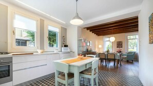 A modern kitchen with a dining area, featuring a checkered floor, a dining table with chairs, and a kitchen counter with appliances. - Beautiful private villa for 5 people with WIFI, A/C and patio (San Daniele Del Friuli)