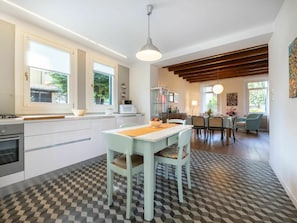 Cozinha moderna com área de jantar, destacando piso xadrez, mesa de jantar com cadeiras e bancada com eletrodomésticos.