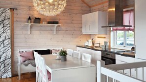 A modern kitchen with white cabinetry, a hanging light fixture, and a dining area with a white table and chairs. - 11 Person Holiday Home in Oyer (Øyer)