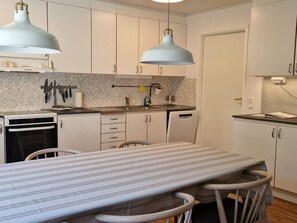 Una cocina moderna con armarios blancos, una mesa a rayas y dos lámparas colgantes.