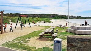 A beach with a swing set, picnic tables, and a flagpole. - Holiday Home in Stråvalla (Stråvalla)
