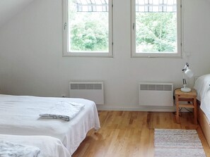 Ein Schlafzimmer mit zwei Betten, einem Nachttisch mit Lampe und zwei Wandlüftungsgittern.