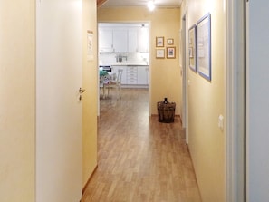 A hallway leading to a kitchen with white cabinets and a dining area. - Holiday Home in Stråvalla (Stråvalla)