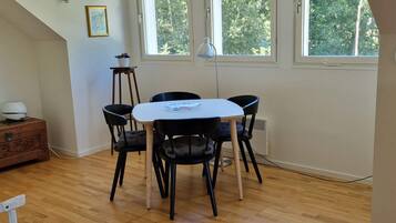 A dining area with a table and four chairs, a standing lamp, and a window with a view of trees.
