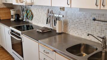 A modern kitchen with white cabinets, a stainless steel sink, and a tiled backsplash.
