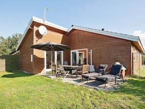 A wooden house with a patio area, a table, chairs, and a lounge chair. - 6 Person Holiday Home in Asnaes-by Traum (Asnaes)