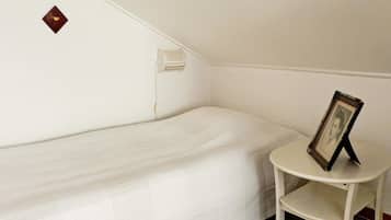 A single bed in a room with a small table and a picture frame.