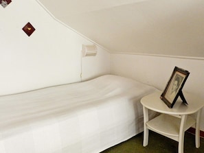 A single bed in a room with a small table and a picture frame. - 6 Person Holiday Home in Brastad (Brastad)