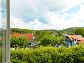 A residential area with houses, dense greenery, and a clear sky.