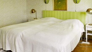 A neatly made bed with a green headboard in a room with a patterned wall and a painting above it. - 6 Person Holiday Home in Brastad (Brastad)