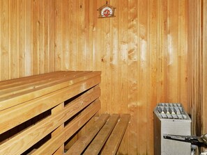 En träbänk i bastun och en bastuaggregat i ett trärum.