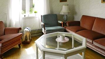 A living room with a brown sofa, a grey armchair, a white coffee table with a cup, and a small dog statue.