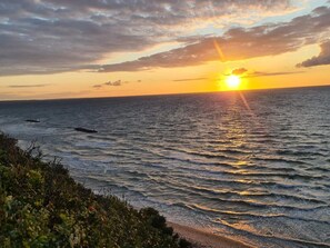 A sunset over the ocean with waves and a beach in the foreground. - 5 Star Holiday Home in Frederiksvaerk (Frederiksvaerk)