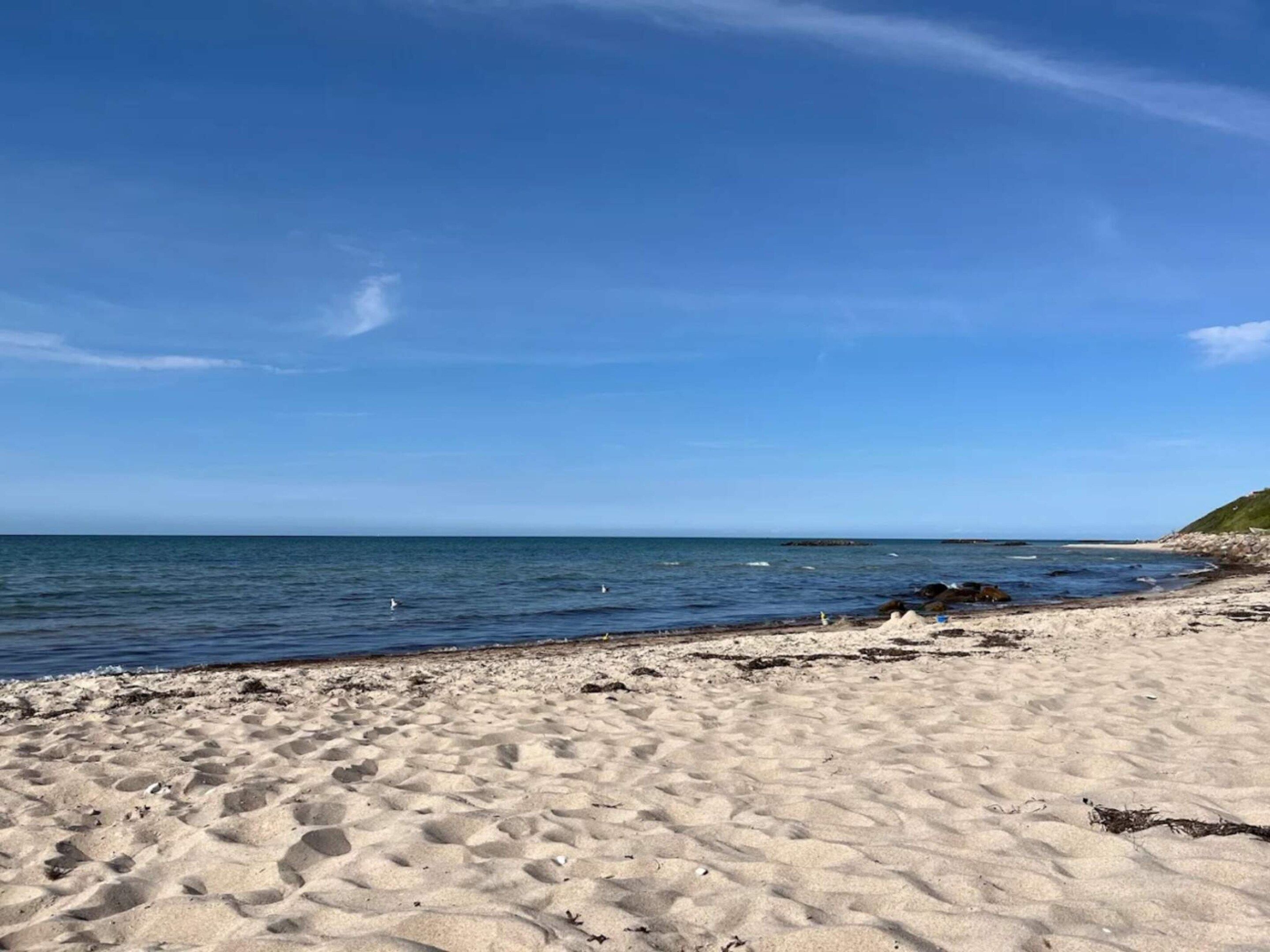 A sandy beach with clear blue water and a distant shoreline.