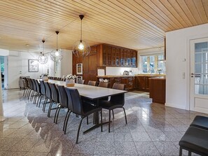 A modern kitchen with a dining area, wooden ceiling, and a large window. - 5 Star Holiday Home in Frederiksvaerk (Frederiksvaerk)