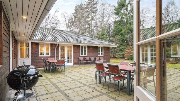 A covered patio with a barbecue grill, outdoor seating, and a view of a house with a tiled roof. - 5 Star Holiday Home in Frederiksvaerk (Frederiksvaerk)