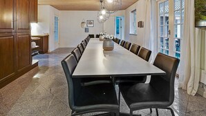A long dining table with chairs, a wooden ceiling, and a chandelier. - 5 Star Holiday Home in Frederiksvaerk (Frederiksvaerk)